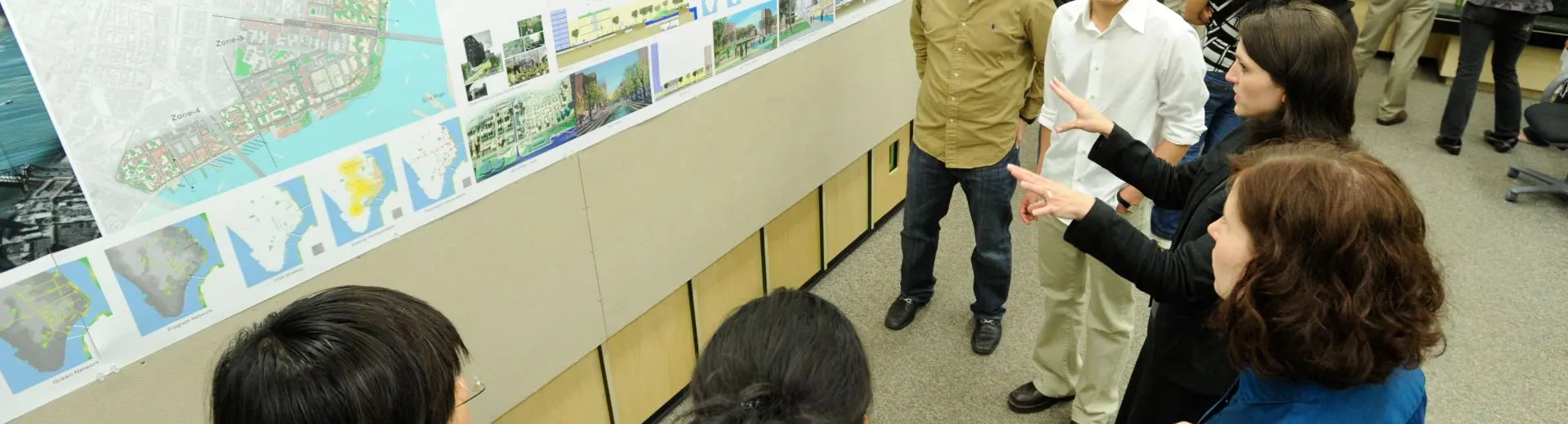 People discussing a presentation with maps on a wall